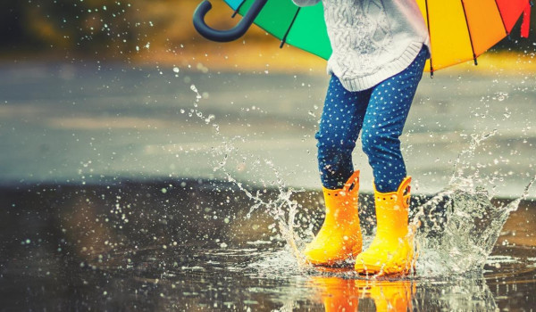 Girl in wellies splashing in a puddle
